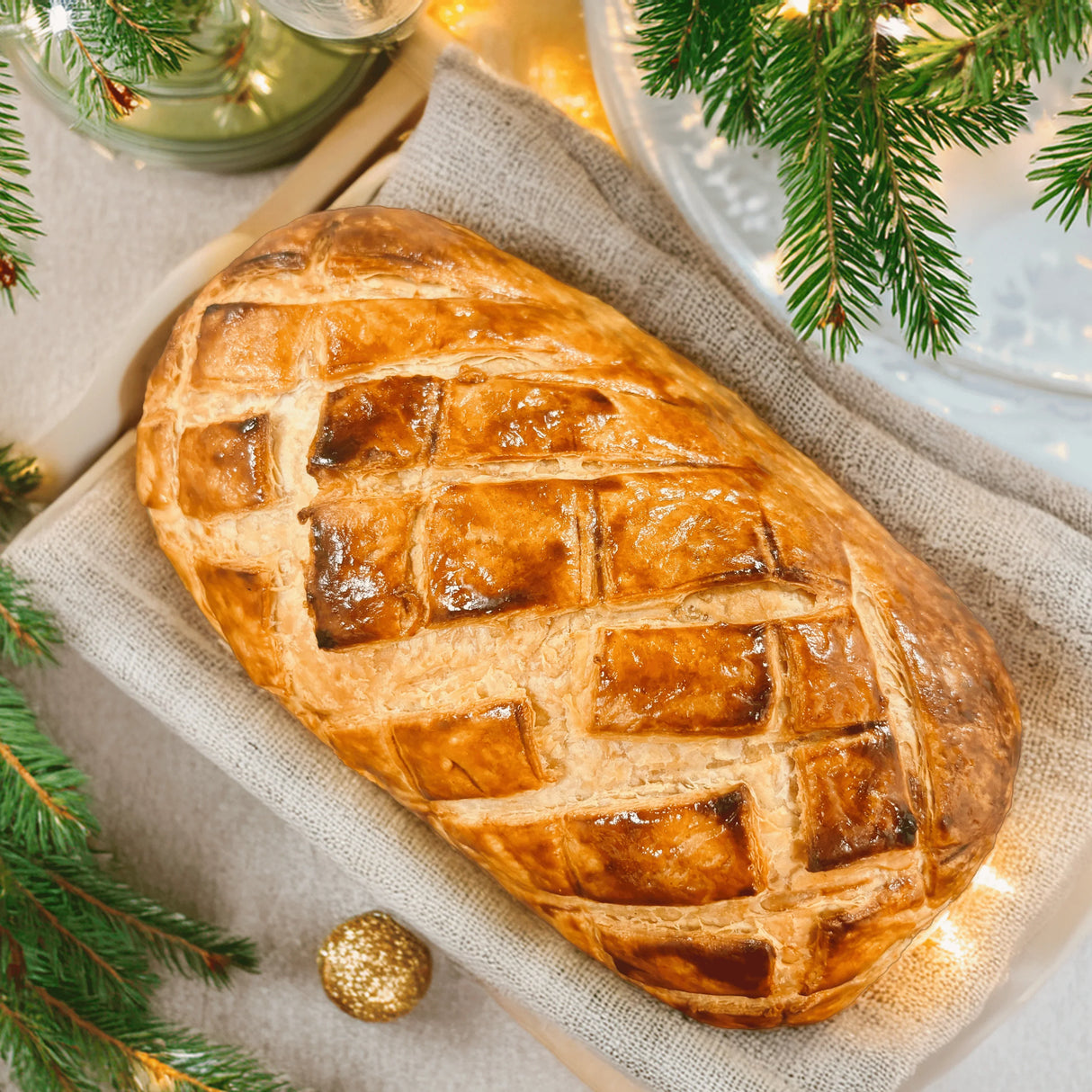 Golden puff pastry Lobster Wellington on linen cloth with festive Christmas decor