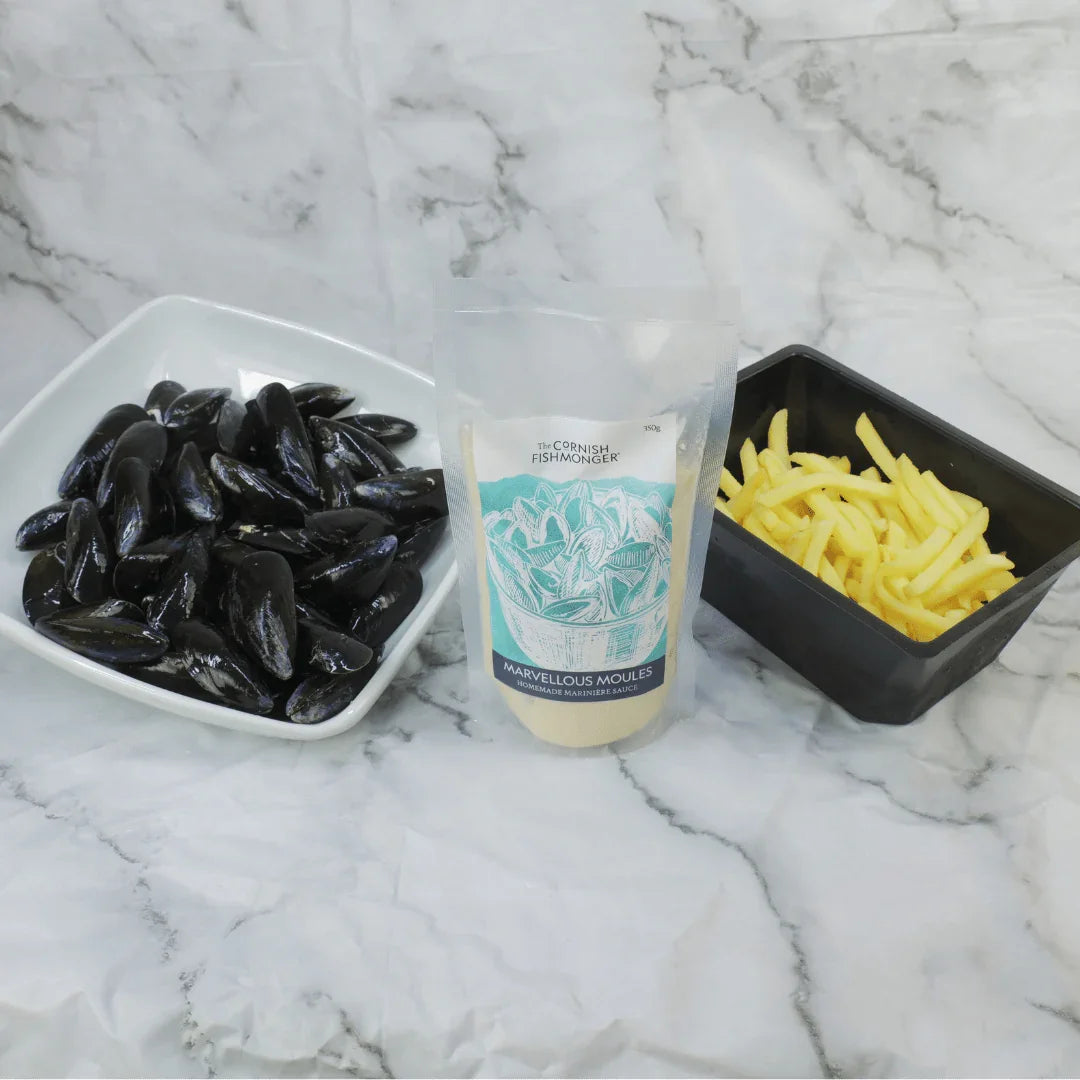 Fresh mussels in a bowl, fries, and marinière sauce kit on marble background