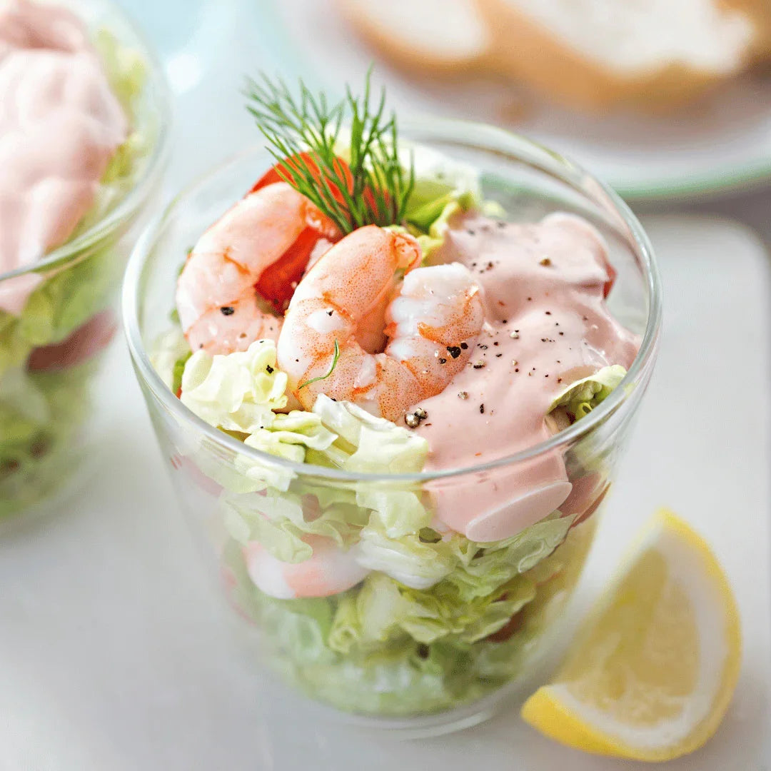 Fresh prawn cocktail with lettuce, Marie Rose sauce, dill, and lemon wedge in glass