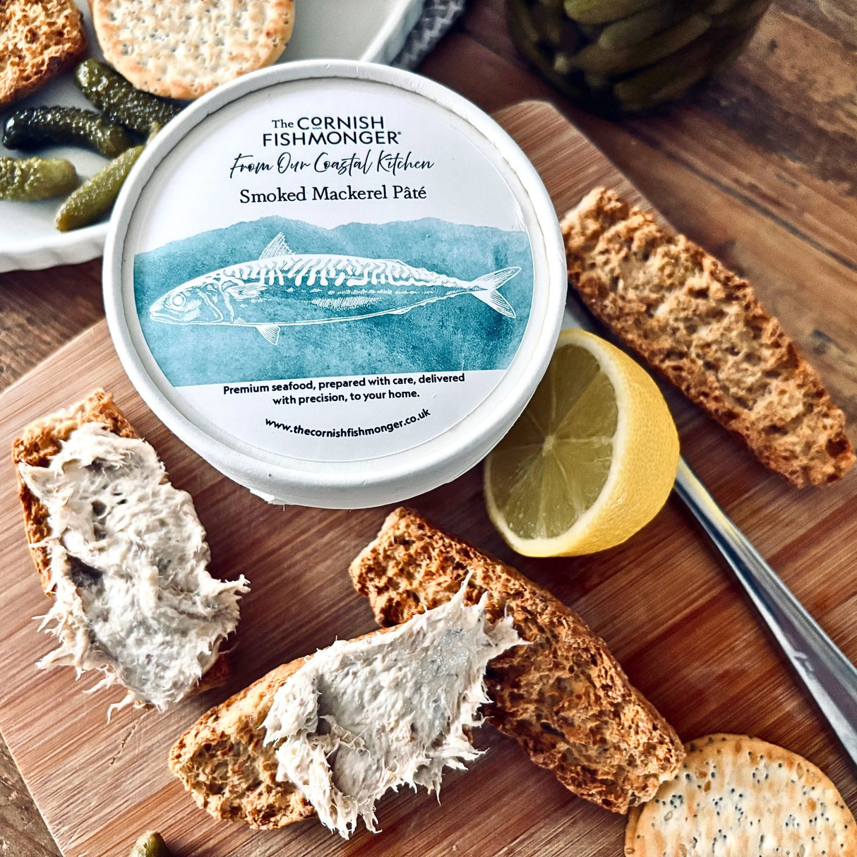 Smoked mackerel pâté spread on toasted bread with lemon, crackers, and pickles