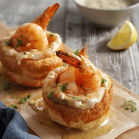 Fresh prawn tartlets in golden pastry with creamy sauce and herbs, served with lemon wedge