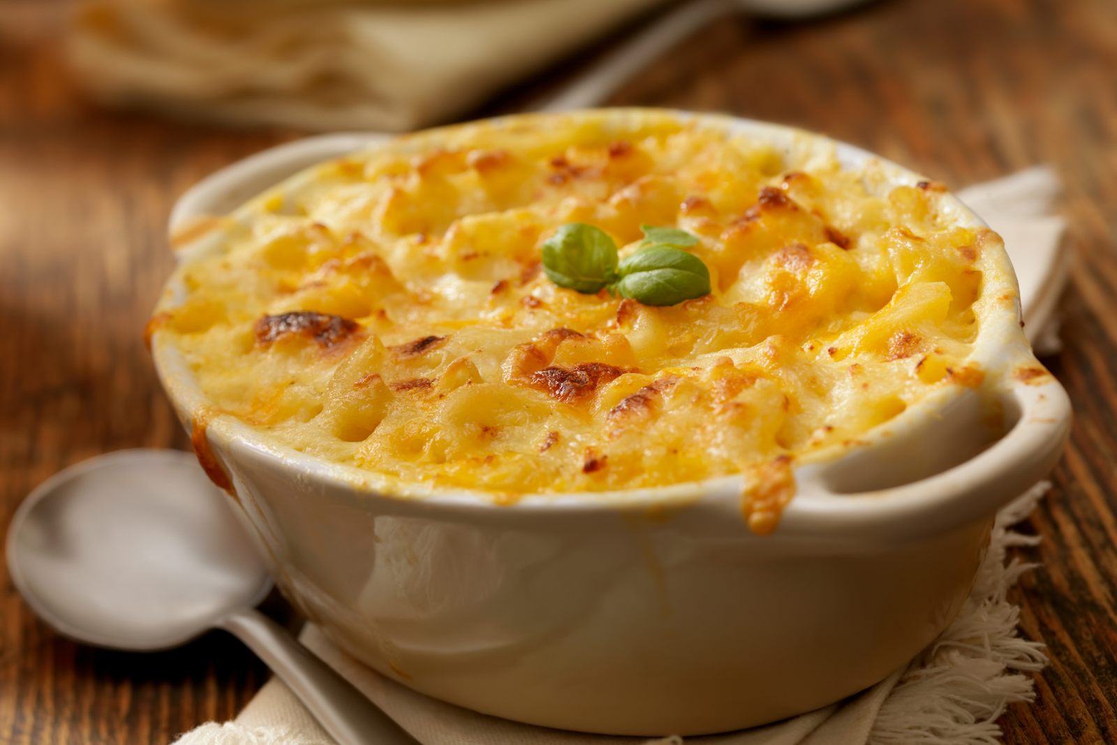 Creamy crab macaroni bake with golden cheese crust in a white dish on a wooden table