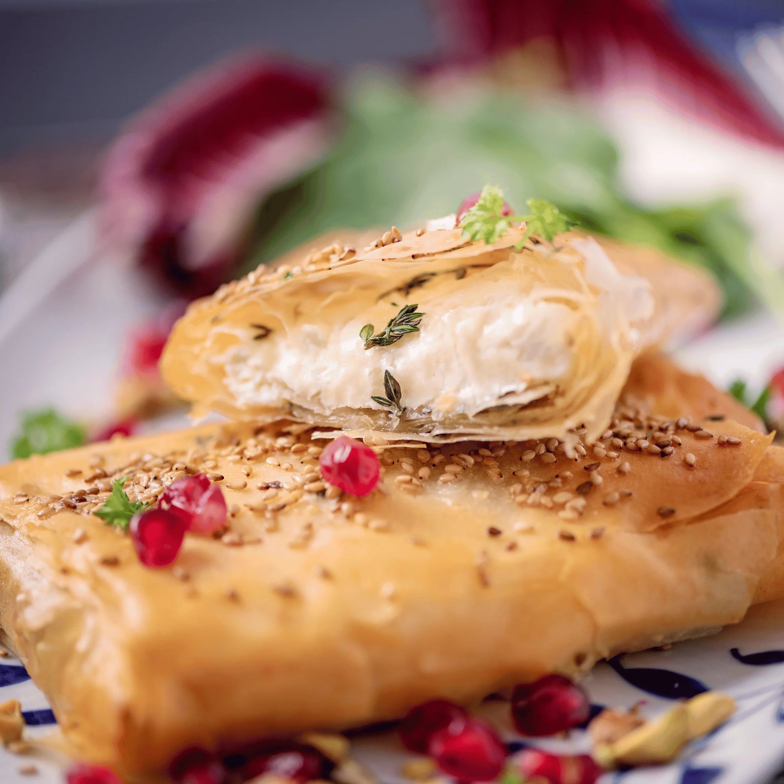 Filo pastry wrapped baked brie with crab, sprinkled with sesame seeds and pomegranate seeds