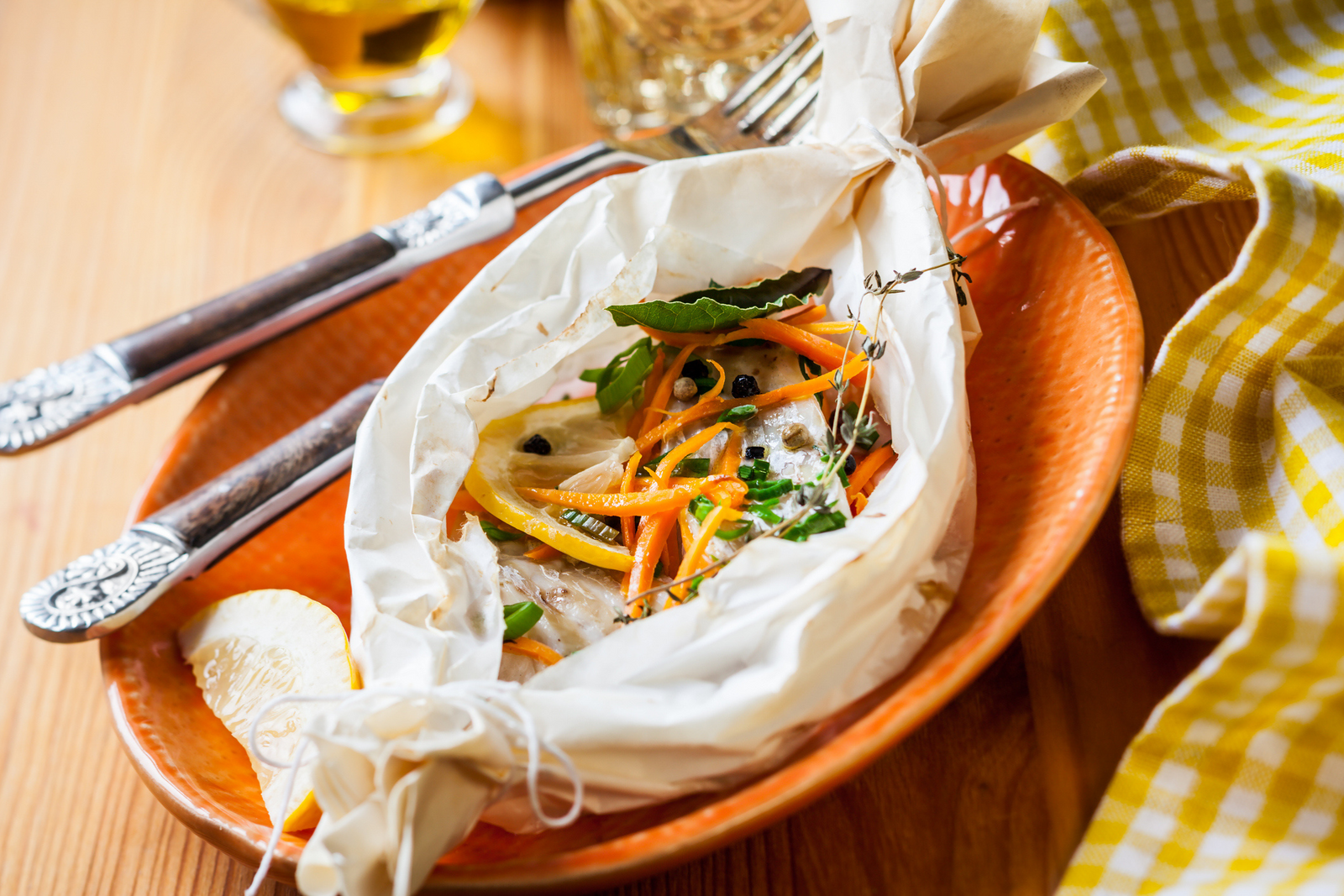 Lemon sole en papillote with lemon slices, carrots, herbs, served on a plate