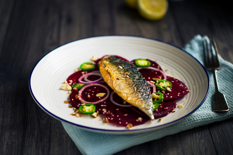 Grilled mackerel fillet on beetroot salad with red onion and sliced green chili on a plate