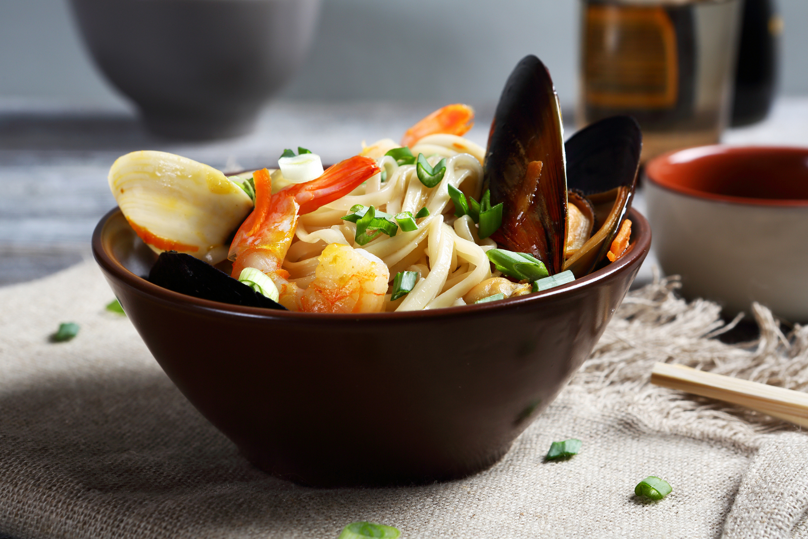 Seafood noodle bowl with mussels, prawns, clams, and green onions