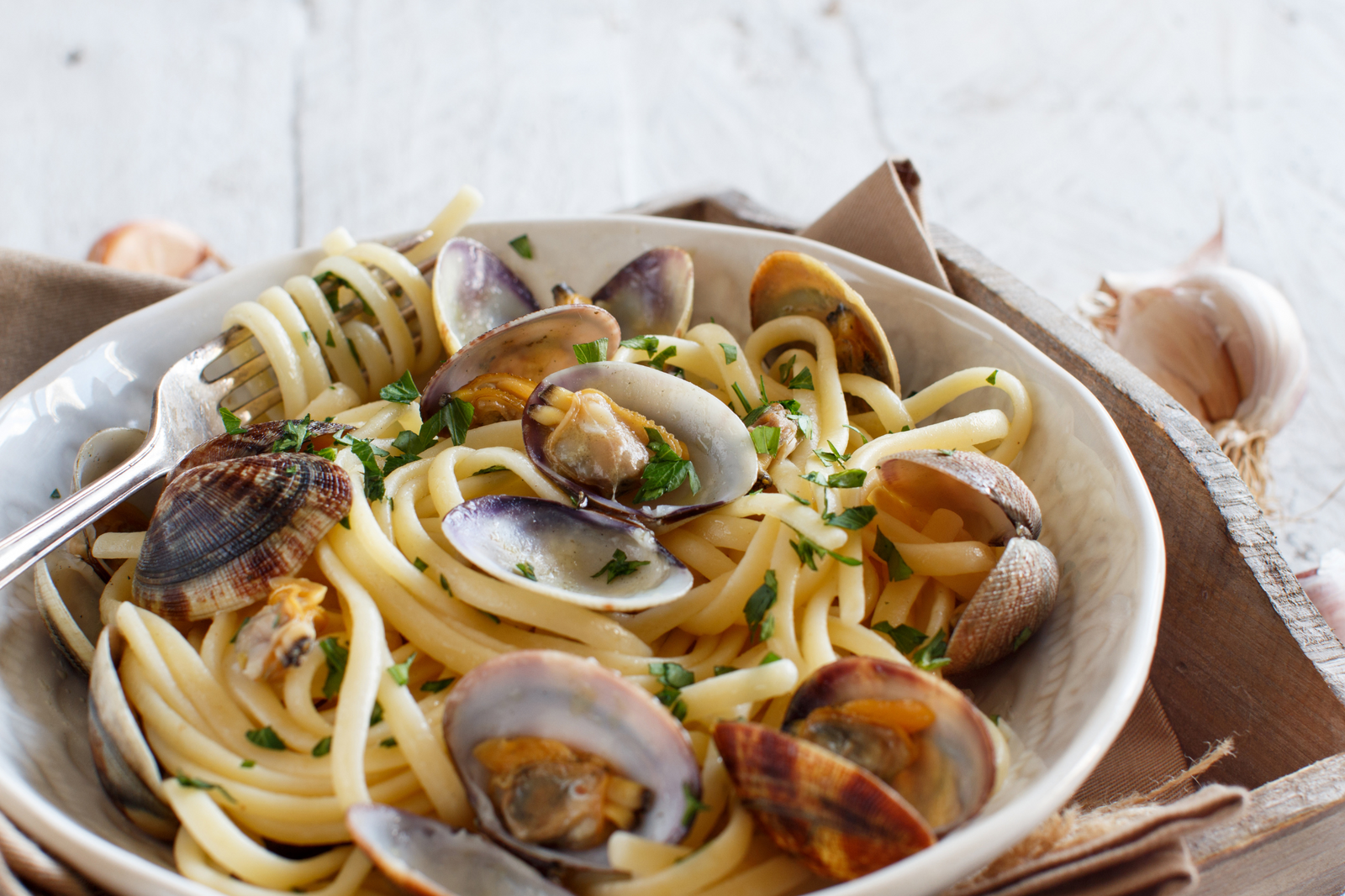 Linguine pasta with fresh clams, parsley, and garlic in a white bowl