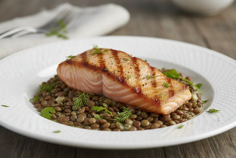 Pan-seared salmon fillet served on a bed of cooked lentils with fresh herbs