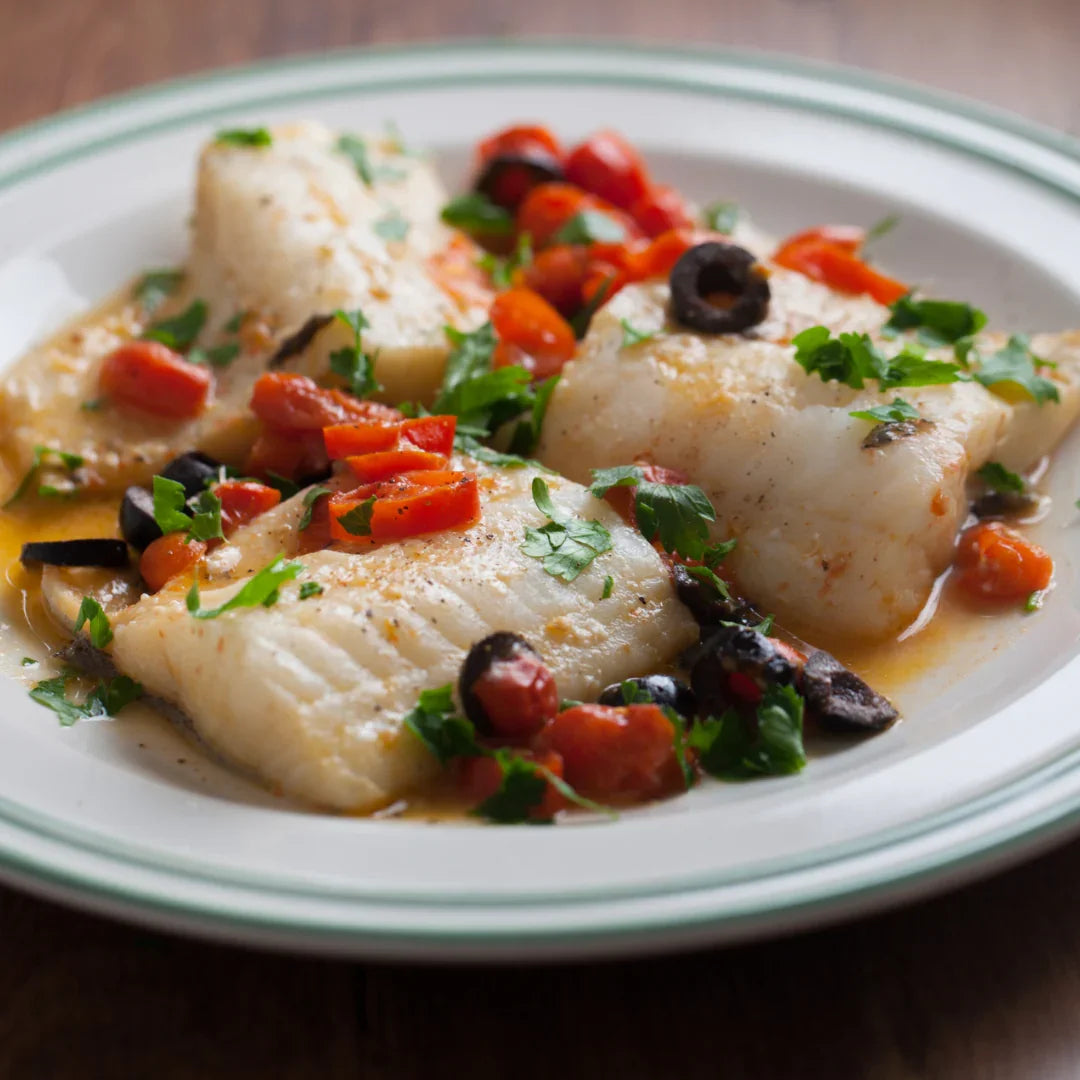 Mediterranean plaice fillets served with tomatoes, black olives, and fresh herbs on a plate
